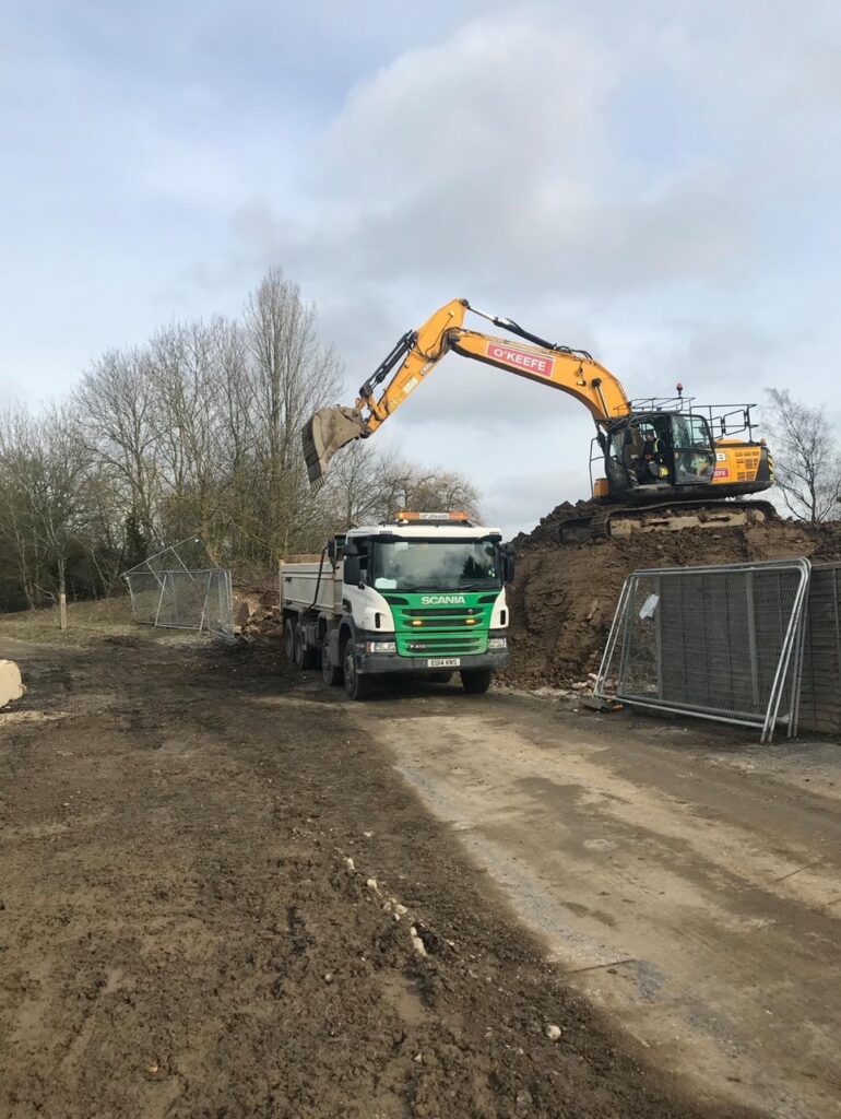 Excavator loading soil into a dump truck at a construction site for earthmoving and excavation services, featured in a web design case study designed by Cheap Website Designer.