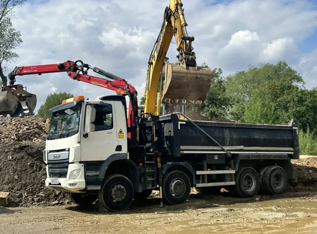 Excavator loading construction waste into a dump truck for earthmoving and site clearance services, featured in a web design case study designed by Cheap Website Designer.
